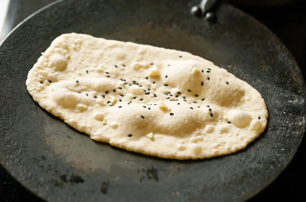 Garlic naan bubbling and puffing up on a hot skillet
