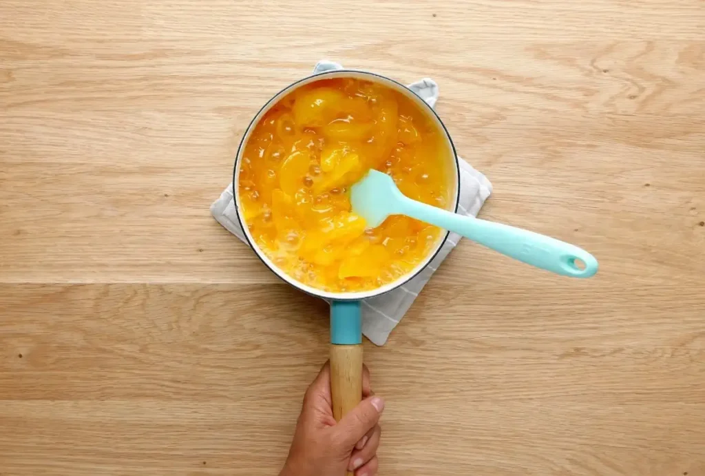 Sliced fresh peaches being tossed for a fresh peach crisp filling