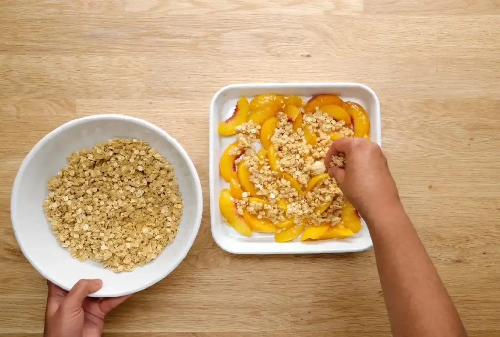 Unbaked peach crisp with fresh peaches topped with oat crumble